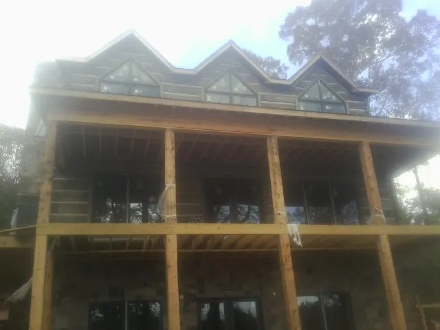 Dormers and porch framing on a large log home under construction in Melrose