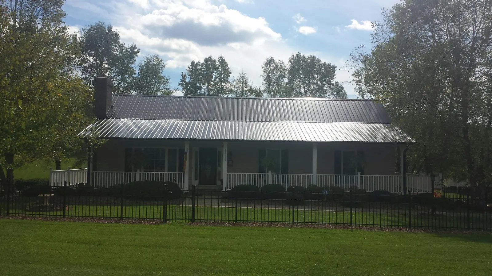 Gray metal roof on a brick ranch with a full width front porch — Gutter Guard Installation work by our crew in Melrose